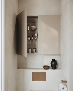 Ett litet beige väggskåp ovanför wc